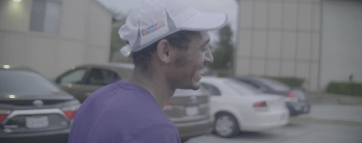A man smiles while walking in a parking lot