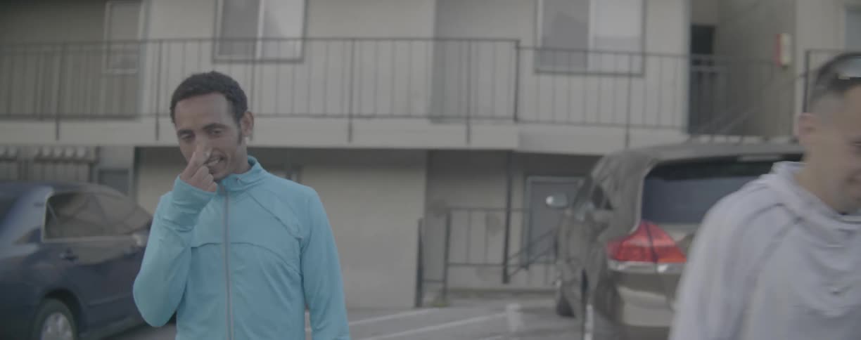 Two men talk while walking in a parking lot