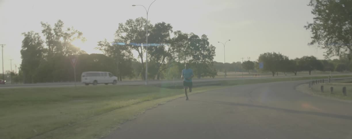 Man is jogging on side street as sun sets
