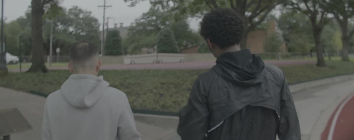 Two men talk while walking outside