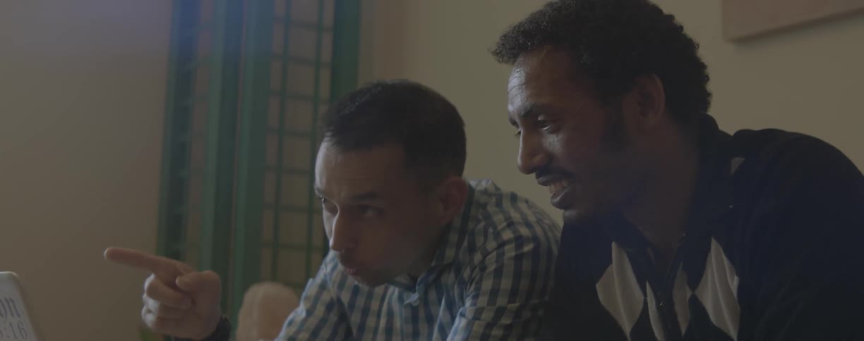 Man points as he sits next to another man
