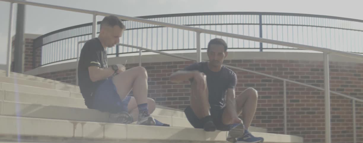 Two men talk while sitting on concrete steps