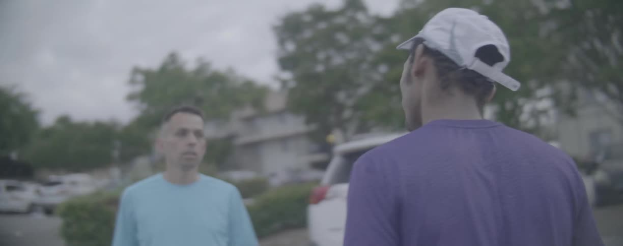 Two men talk while walking in a parking lot