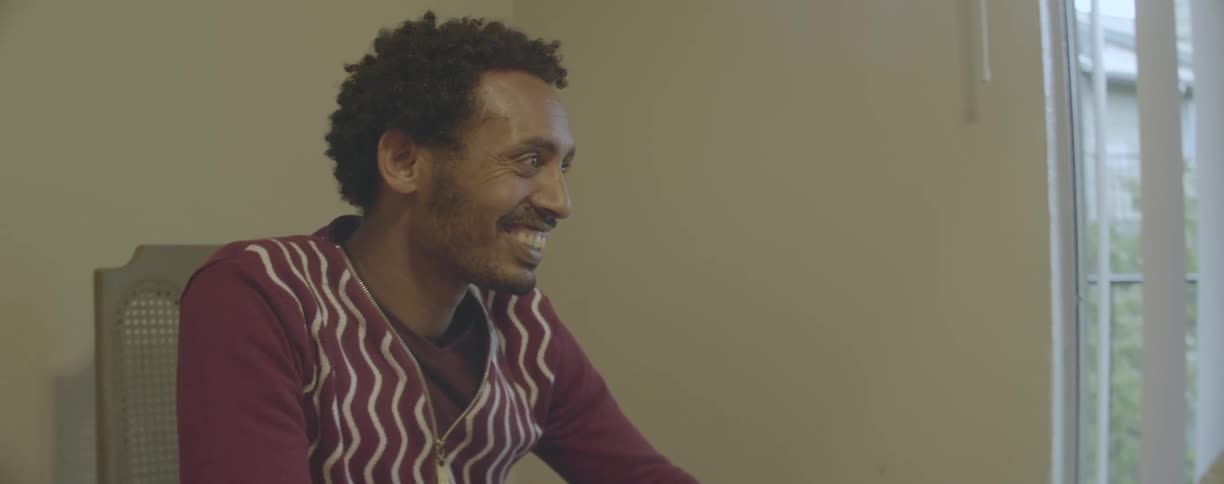 A man smiles and nods while talking