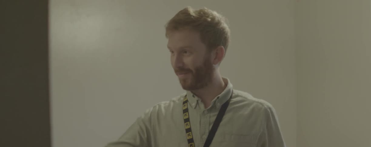 A man smiles while talking indoors