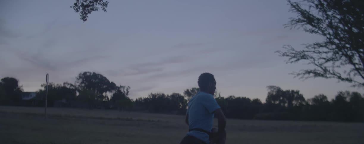 A man stretches in a rural field at dusk