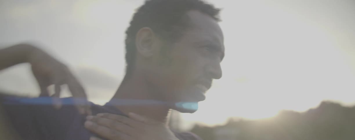 A man rolls his shoulders outside at sunset