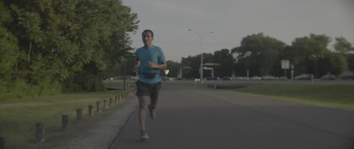 Man runs down the road next to the trees
