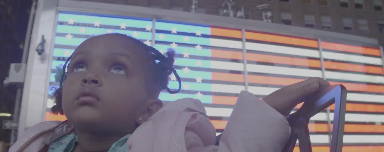 Young girl by neon sign looks upward