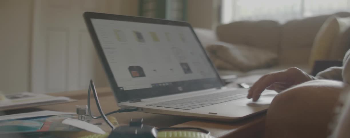 A person scrolls on a laptop at home