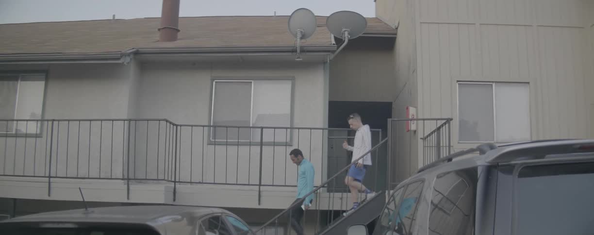 Two men walk down apartment stairs