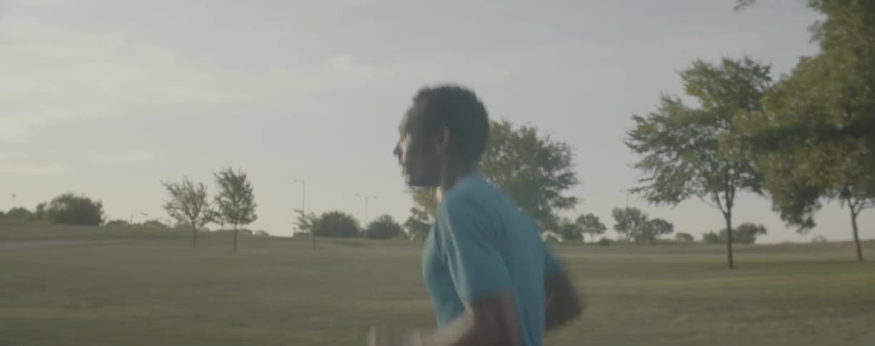 Man is jogging past field on cloudy day