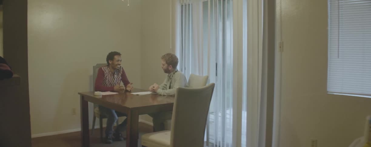 Two men sit at a table talking