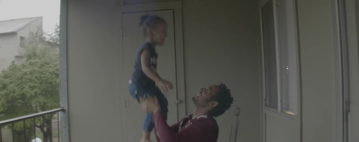 A father plays with his young daughter on a balcony