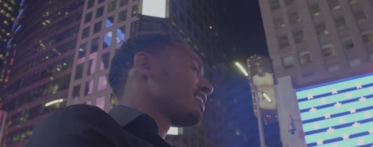 A man smiles while standing on a city sidewalk