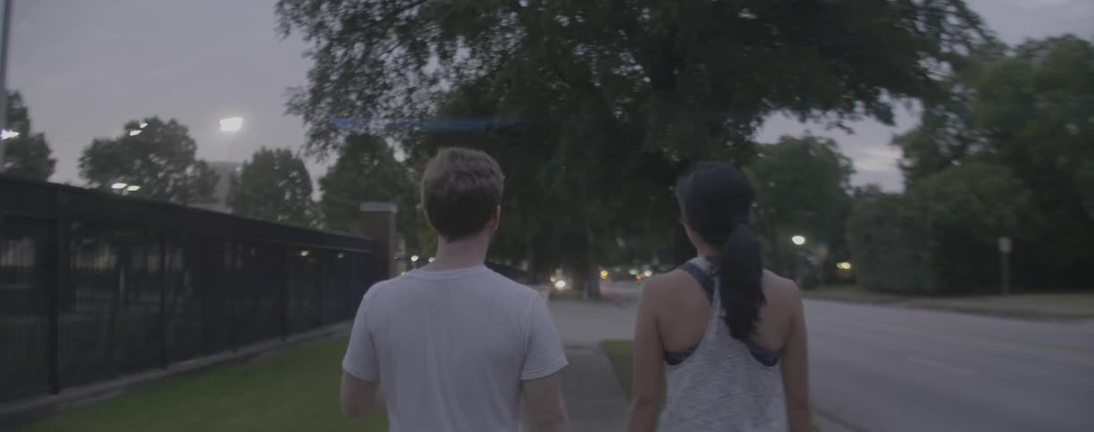 Man and woman walk on a sidewalk at dusk