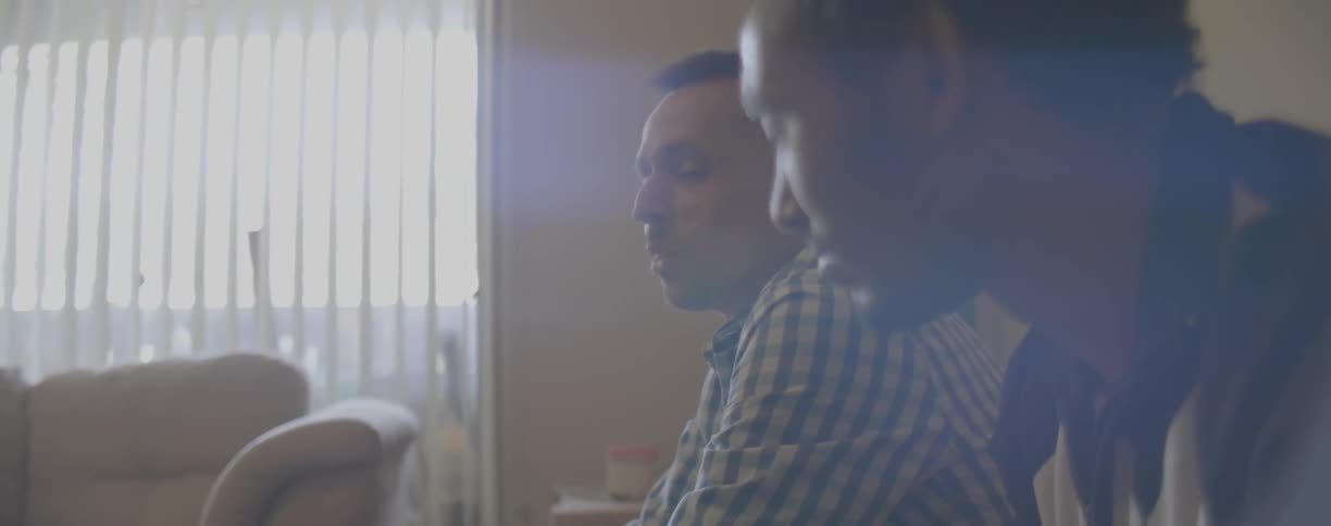 Two men talk in a living room