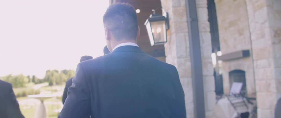 Men in suits walk outside toward a reception hall