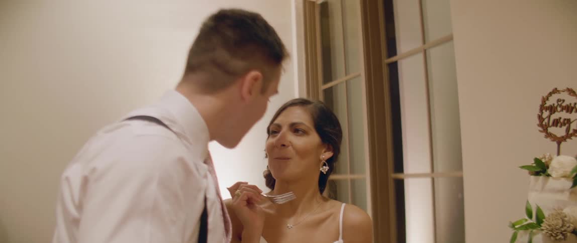 A bride and groom feed each other cake and kiss