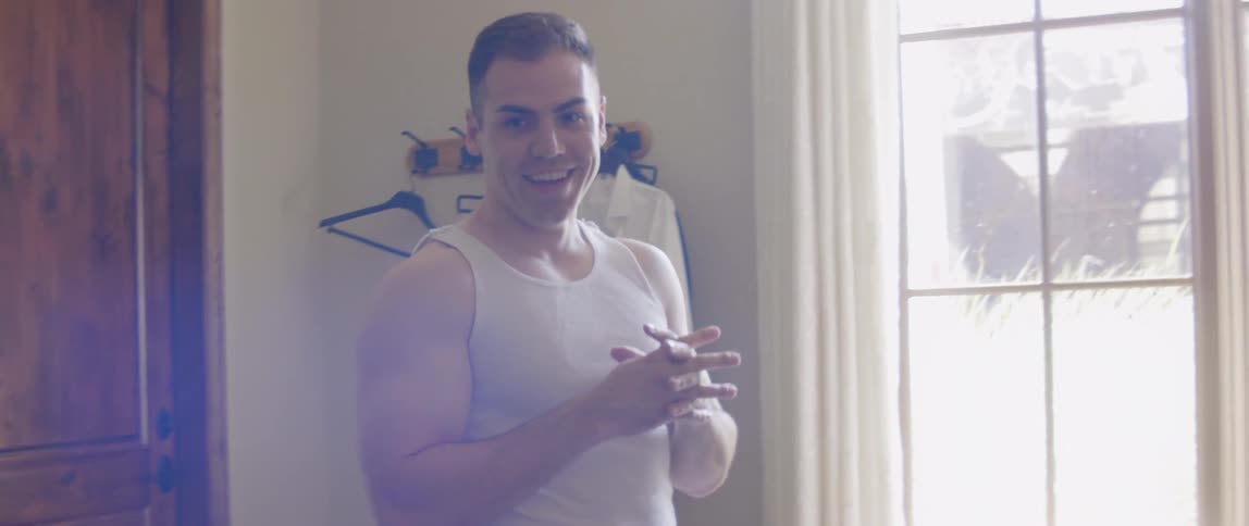 A man smiles while talking near a window