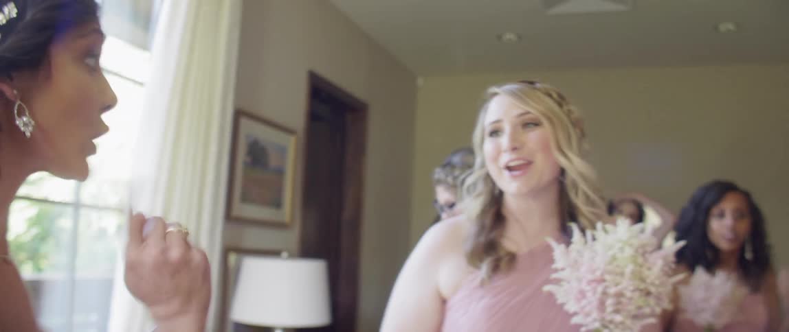 A bridesmaid blows a kiss to the bride as they talk before the wedding
