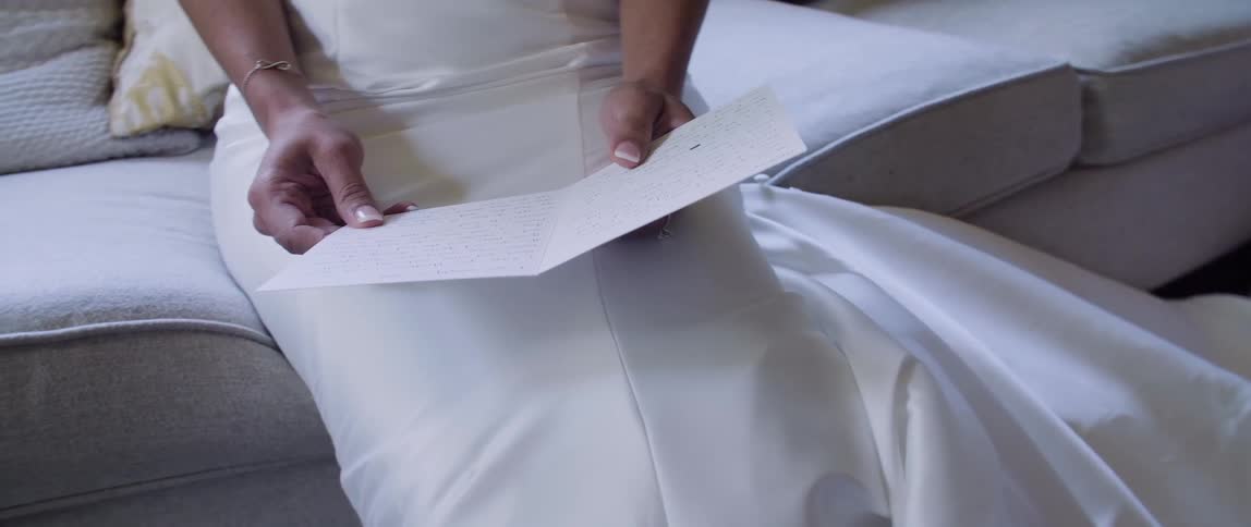 A bride reads a card while sitting on a couch