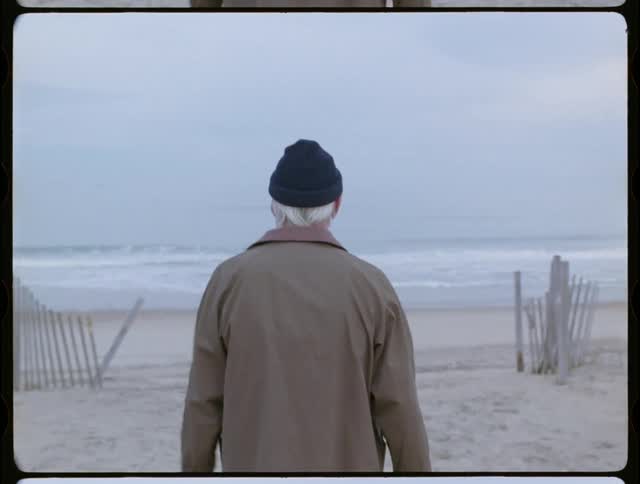An elderly man walks on a sandy beach
