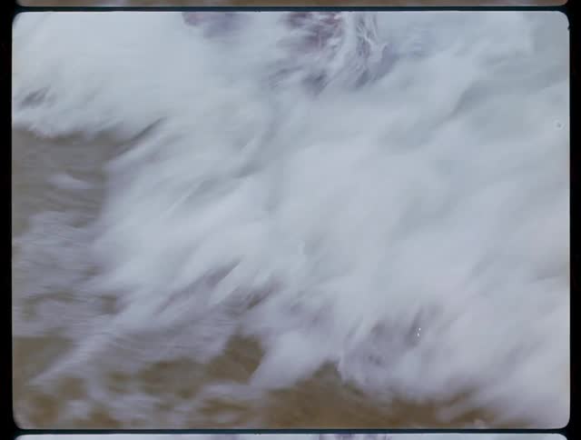 A man wades in the ocean while wearing boots