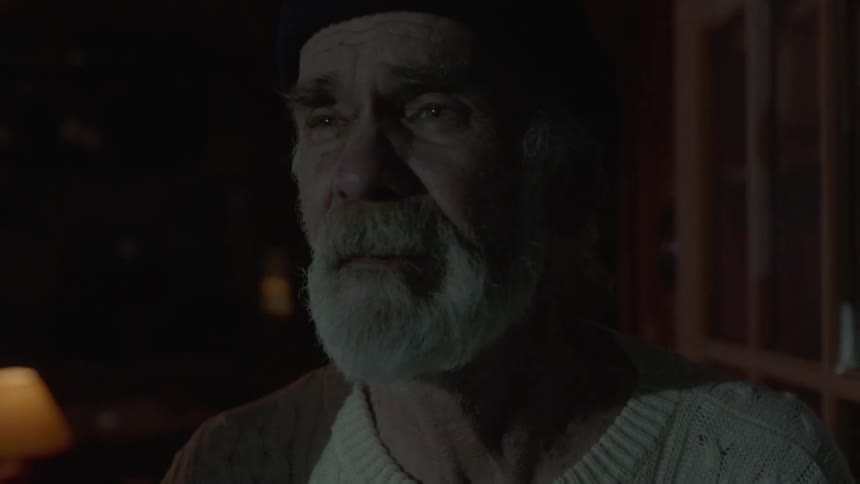An elderly man stands and looks as a light flashes