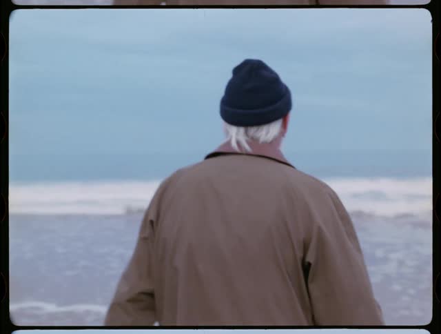 Older man is walking out into the ocean on cloudy day