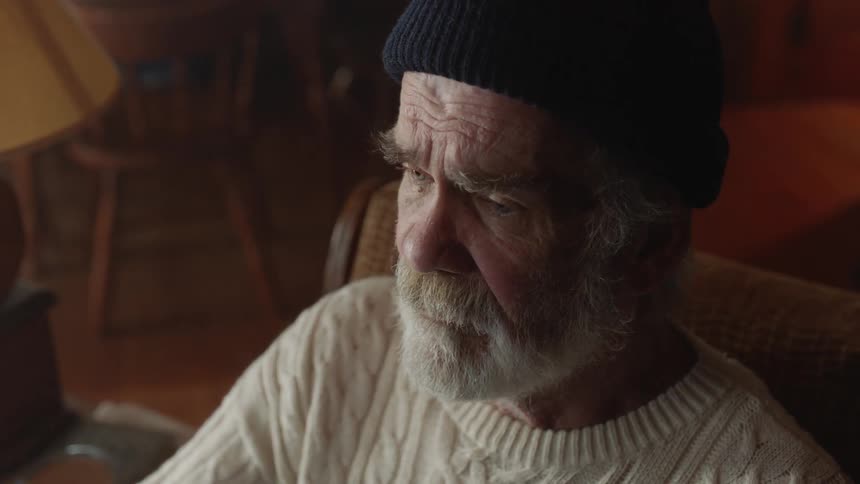 Older man with beard sits and examines something