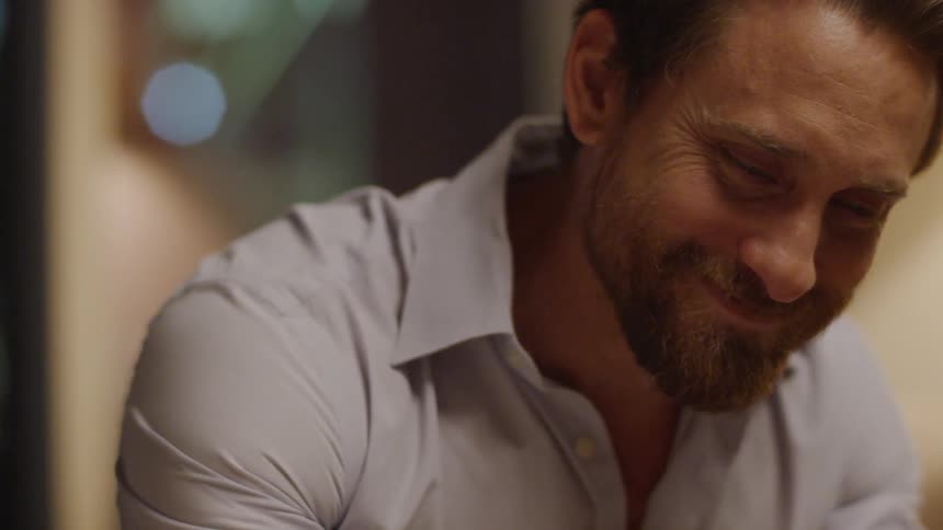 A man sitting down smiles and laughs