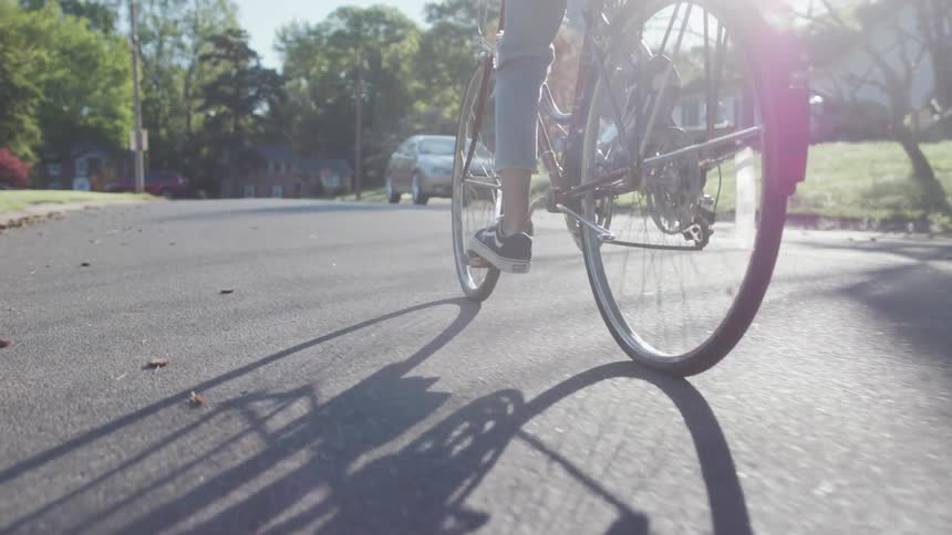 A woman rides a bicycle on a neighborhood street