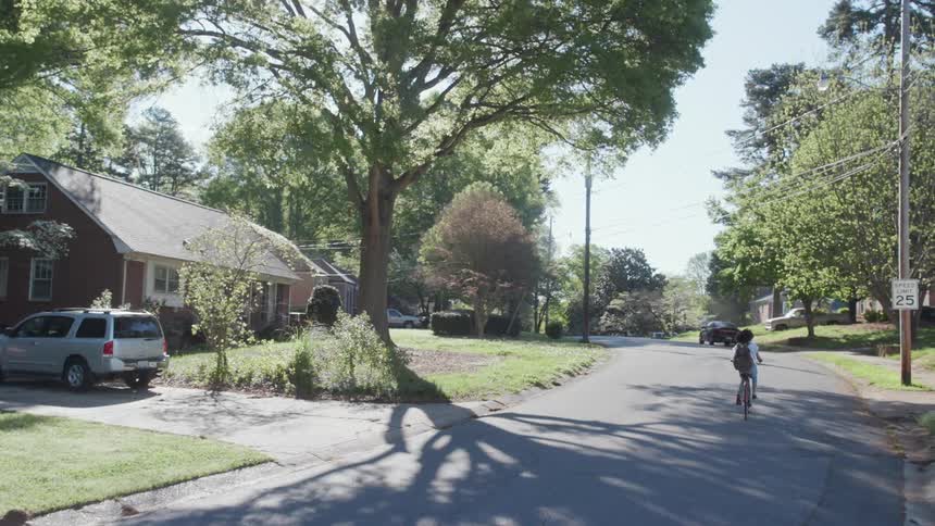 A woman rides her bicycle on the neighborhood street