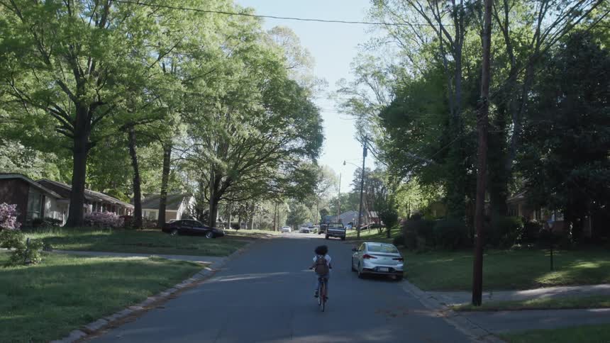 A woman rides a bicycle on a suburban street
