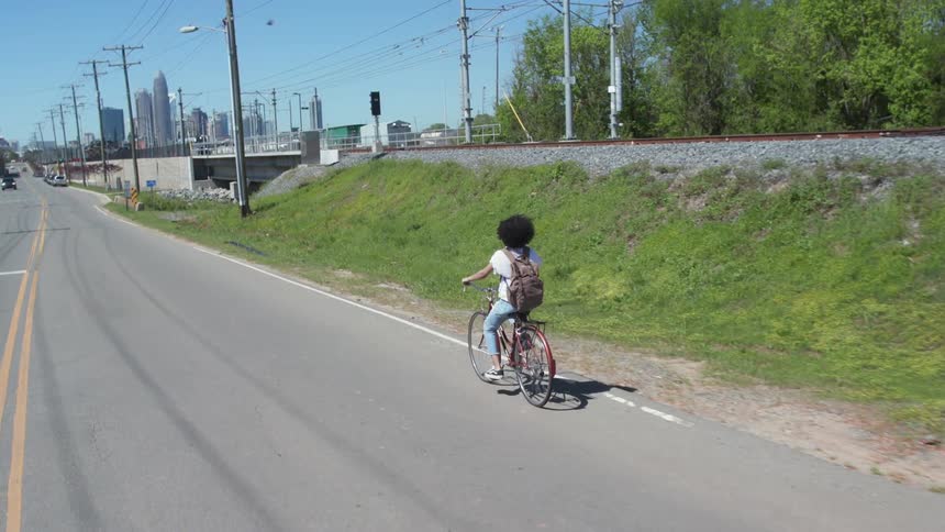 A woman rides her bike down the street