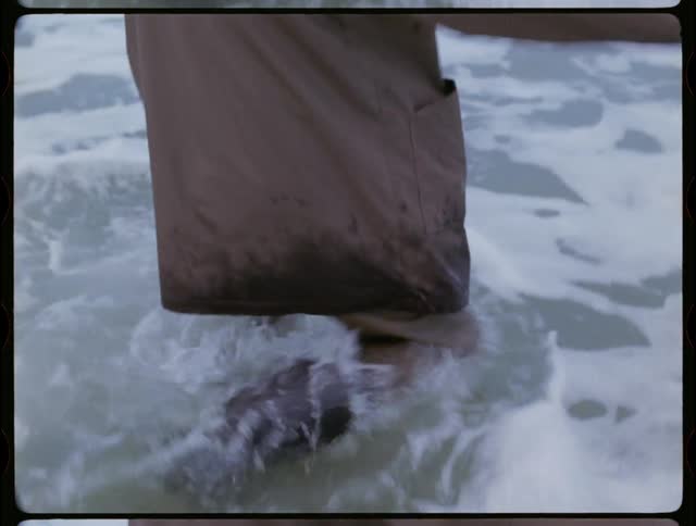 A clothed man walks into an ocean