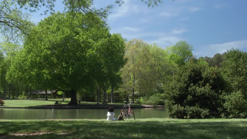 Woman sits next to a river by her bike