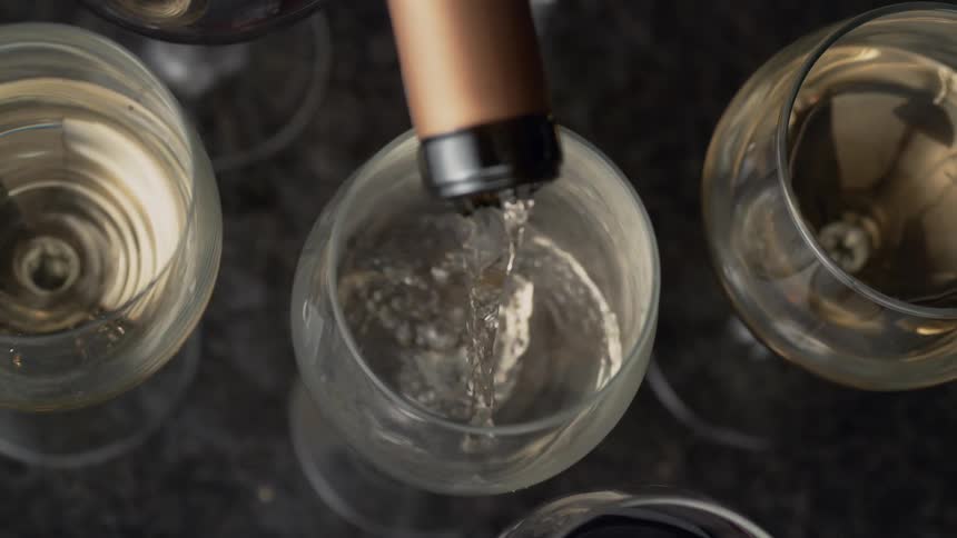 A person pours a drink into a glass