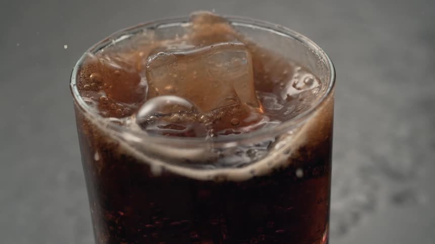 Ice splashing into glass of cola