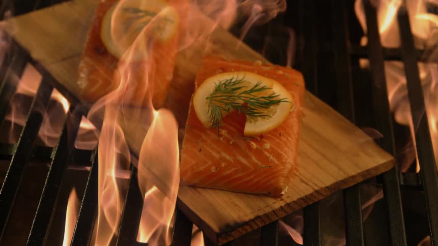 Cedar plank salmon on a grill as flames envelop it