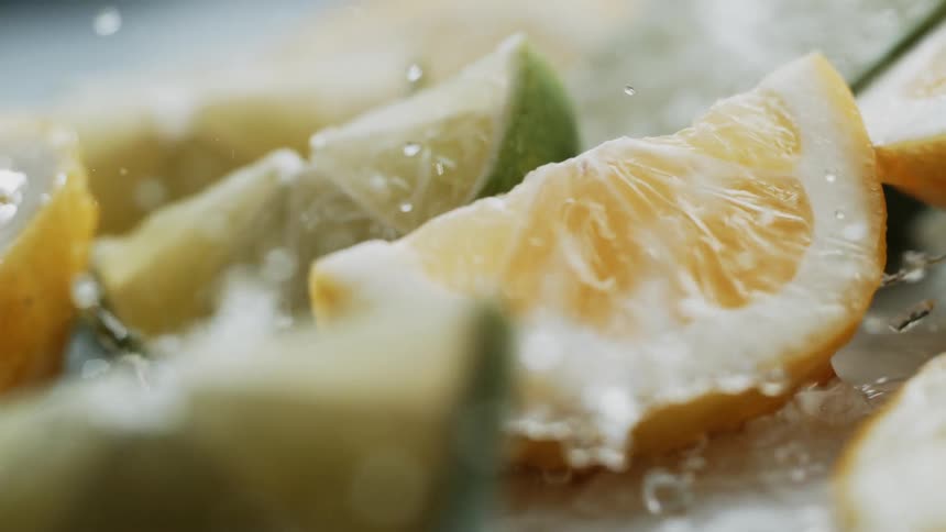 Water splashing onto lemon and lime in slow motion