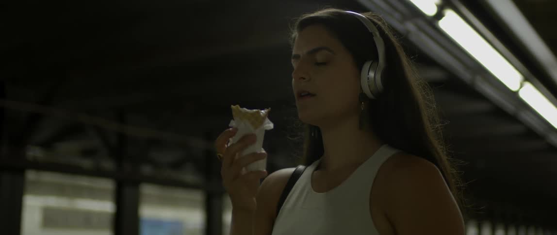 A woman eats an ice cream cone in a subway station