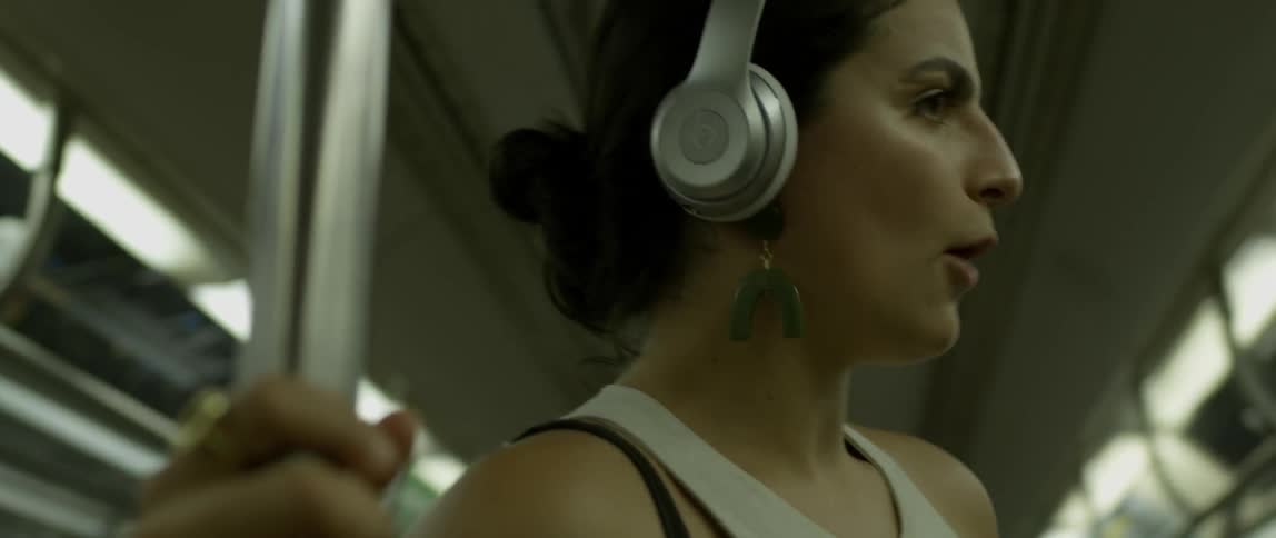 A woman wearing headphones dances and sings on the subway