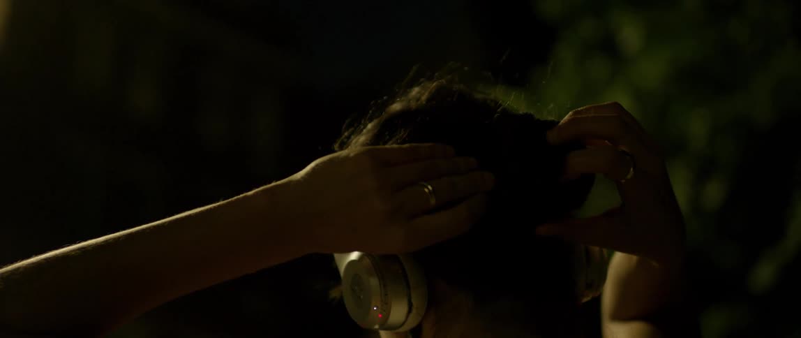 Woman tying her hair up while listening to music at night