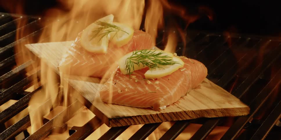 Salmon is cooked on a wood slat on the grill