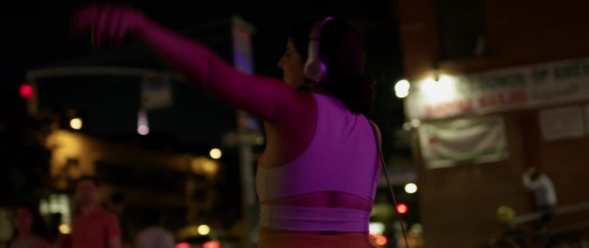 A woman dances playfully on the street at night