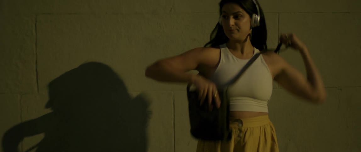 A woman dances next to a building while wearing headphones