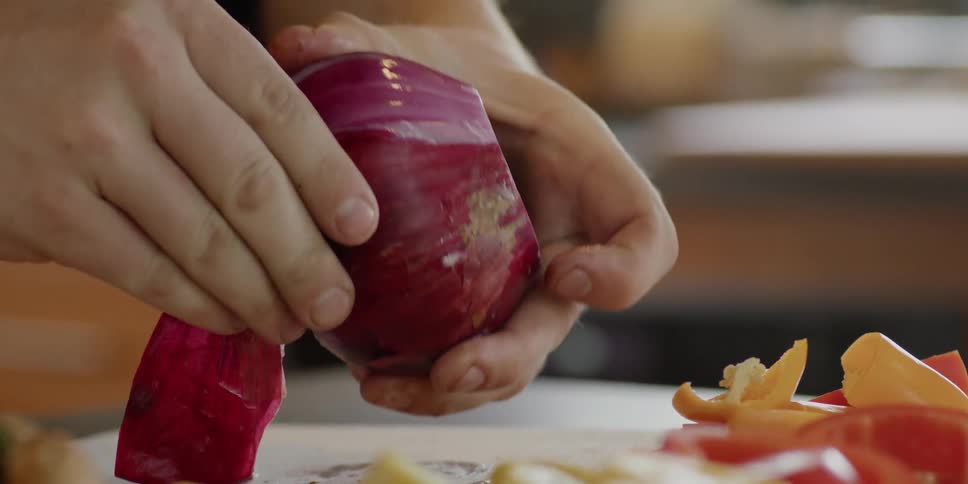 Man cuts a red onion and vegetables
