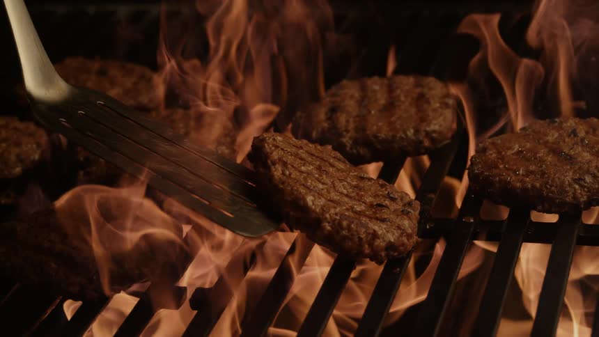 Burgers are flipped on the grill